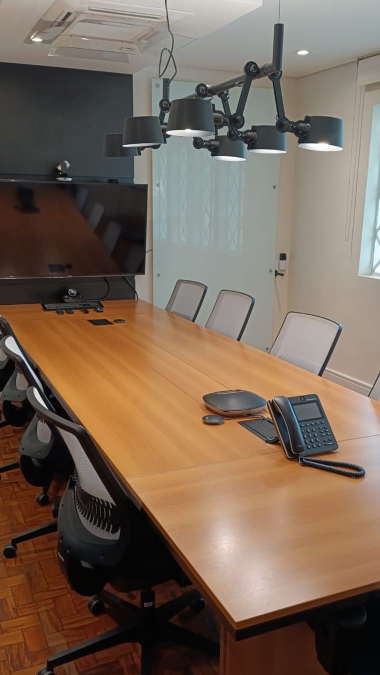 Sala de reunião corporativa com telefone IP, sistema de videoconferência e ponto de rede cabeado na mesa