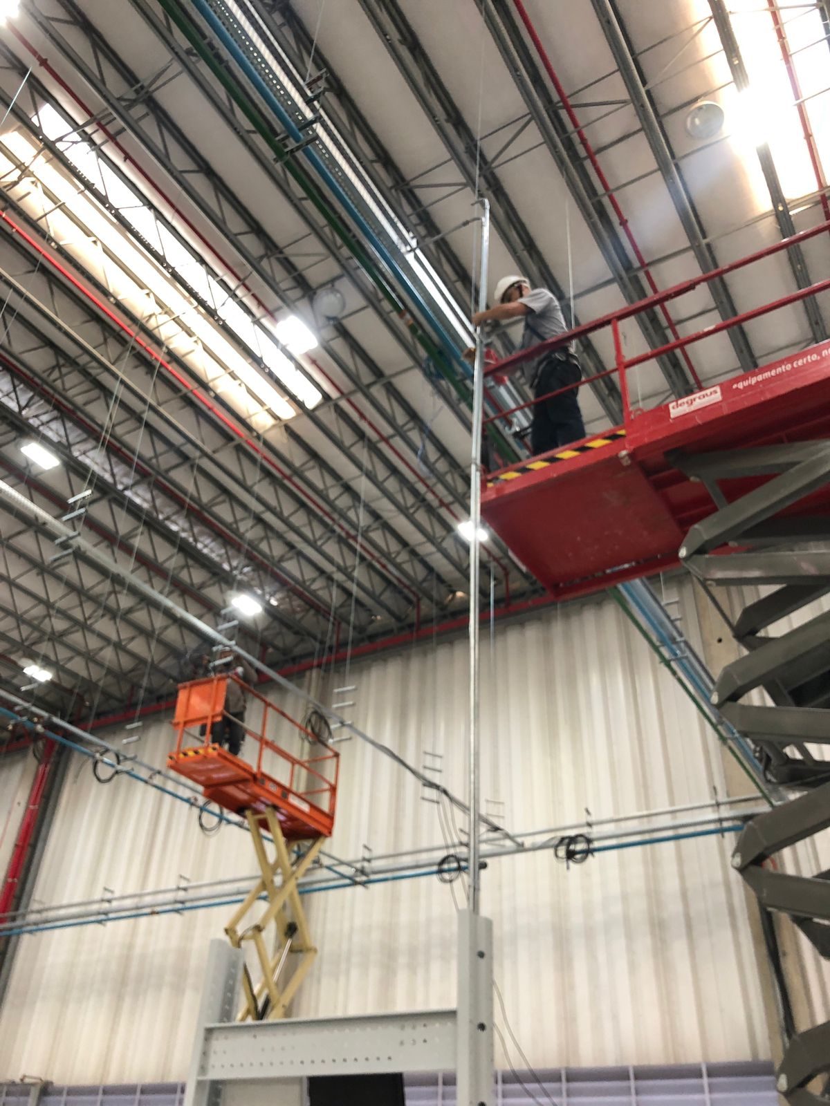 Instalação de cabeamento em altura, com plataforma elevatória, em galpão industrial