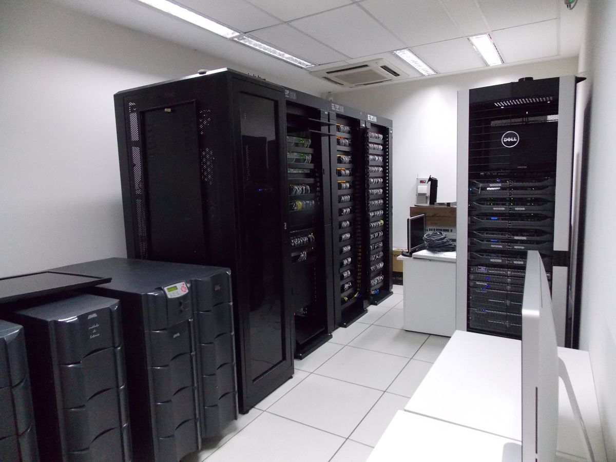 Sala técnica com racks de servidores e switches, nobreaks e cabeamento organizado